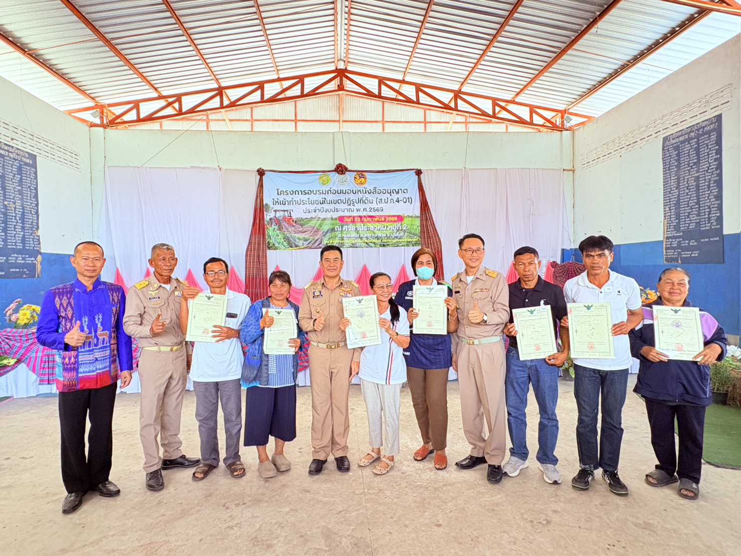 title - วันที่ 23 กุมภาพันธ์ 2569 นายประเสริฐ กาญจนเกียรติกุล ปฏิรูปที่ดินจังหวัดบุรีรัมย์ พร้อมเจ้าหน้าที่ ส.ป.ก.บุรีรัมย์ จัดโครงการอบรมก่อนมอบหนังสืออนุญาตให้เข้าทำประโยชน์ในเขตปฏิรูปที่ดิน (ส.ป.ก. 4-01) โดยมีนายคำเคลื่อน พณะชัย รองผู้ว่าราชการจังหวัดบุรีรัมย์ เป็นประธานในการมอบ ส.ป.ก. 4-01, โฉนดเพื่อการเกษตร แก่เกษตรกรที่เข้าร่วมโครงการ และร่วมรณรงค์ลดการเผาในเขตปฏิรูปที่ดิน